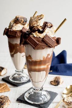 two glasses filled with ice cream and chocolate on top of a table next to crackers