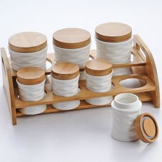 an assortment of white dishes and wooden lids on a tray with two cups next to it