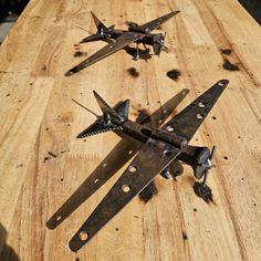 several metal planes are sitting on a wooden table with holes in the middle and nails sticking out of them