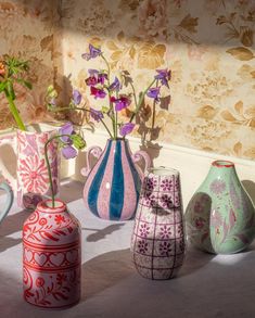 there are many different vases with flowers in them on the table next to each other