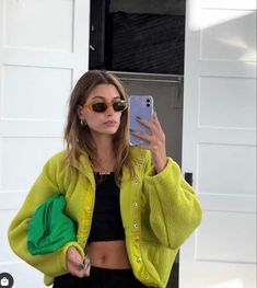 a woman taking a selfie in front of a garage door with her cell phone