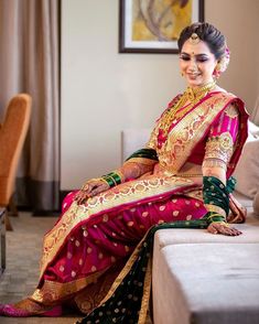 a woman sitting on top of a couch wearing a red and green dress with gold accents