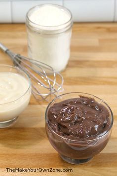 chocolate pudding and cream in small bowls on a wooden table with a whisk