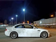 a white car parked on the side of a road at night with street lights in the background