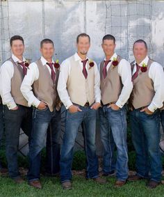 a group of men standing next to each other in front of a wall wearing ties and vests