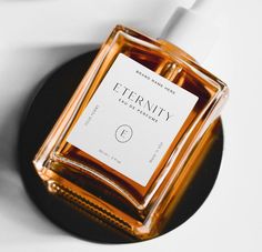 a bottle of perfume sitting on top of a black plate next to a white wall