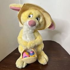 a yellow stuffed animal with a hat on top of it's head sitting on a table