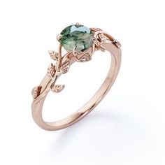 a ring with a green stone and leaves on the side, set in rose gold