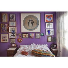 a bedroom with purple walls and lots of pictures on the wall, including a bed