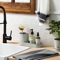 a kitchen sink with soap, toothbrushes and other bathroom items