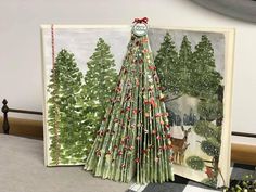 a christmas tree made out of folded paper on the floor next to an open book