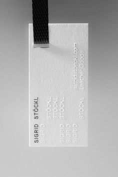 a white business card with a black strap hanging from it's side on a gray background