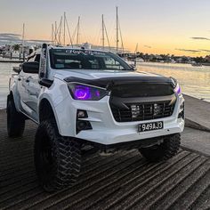 a white pick up truck parked next to the water