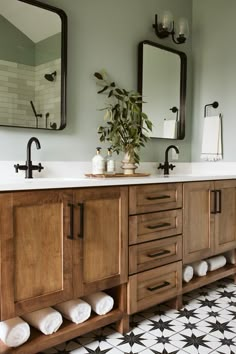 a bathroom with two sinks and mirrors on the wall next to a plant in a vase