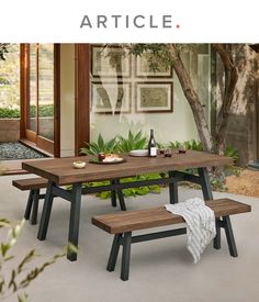 a wooden table with two benches next to it and a bottle of wine on the table