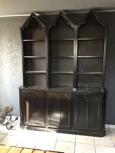 a black bookcase sitting on top of a tiled floor