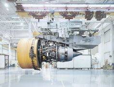 an airplane engine in a large building with other equipment on the floor and around it