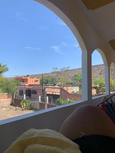 a woman laying on top of a bed in front of an open window next to a building