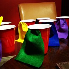 plastic cups are lined up on a table with colorful cloth bags around them and one cup is empty