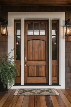 a wooden front door with two lights on each side and a plant in the middle