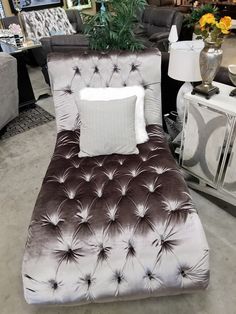 a brown and white chaise lounge chair with pillows on display in a furniture store