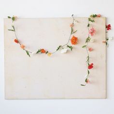 an arrangement of flowers arranged on top of a piece of paper with string attached to it