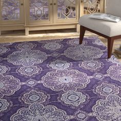 a purple area rug with an ornate design on the front and back, along with a white chair