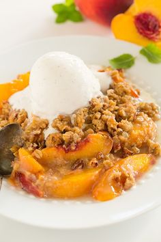 a white plate topped with fruit and ice cream next to peaches on a table