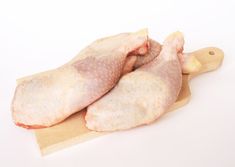 two raw chicken legs on a cutting board with a white background royalty images and clippings