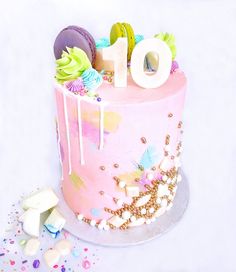 a pink cake with white icing and colorful decorations