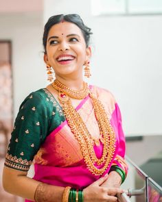 a woman in a pink and green sari smiles while standing next to a railing