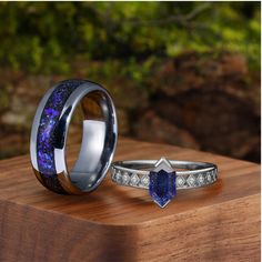 two rings with blue and purple stones on them sitting on top of a wooden table