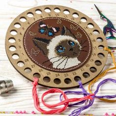 a wooden clock with a cat on it next to some scissors and thread spools