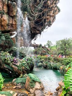 there is a waterfall in the middle of this tropical garden with lots of trees and plants