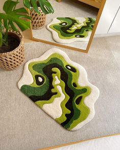 a green and black rug sitting on top of a floor next to a plant in a pot