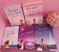 four books are sitting on a shelf next to a pink flower