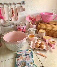 an assortment of kitchen utensils and baking supplies on a counter top with pink dishes