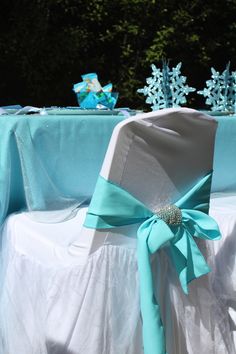 a chair covered in blue and white cloths with a bow on the back of it