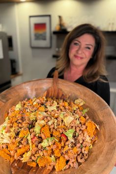 a woman holding a large wooden bowl filled with food