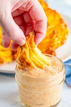 a person dipping some food into a jar