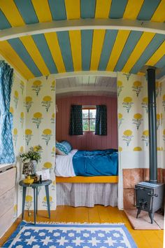 a bedroom with yellow and blue walls, a bed in the corner and a rug on the floor