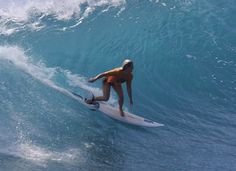 a woman riding a wave on top of a surfboard in the ocean with blue water