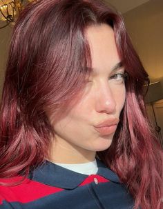 a woman with red hair is looking at the camera while wearing a blue and red striped shirt