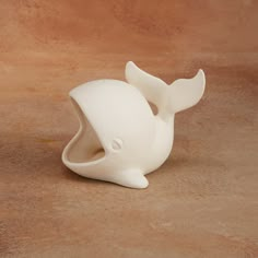 a white whale shaped object sitting on top of a brown floor next to a wall