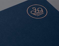 the front cover of a blue book with gold lettering on it and a monogrammed logo