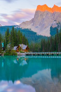 a lake surrounded by mountains and trees with a bridge in the middle that leads to it