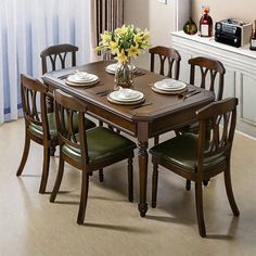 a dining room table with four chairs and a vase filled with flowers on top of it