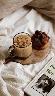 a cup of coffee next to a book on a bed