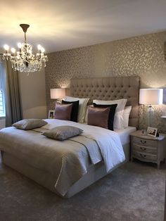 a bedroom with a large bed, chandelier and two lamps on either side of the bed