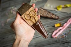 a person holding a pair of scissors in front of some crafting supplies on a table